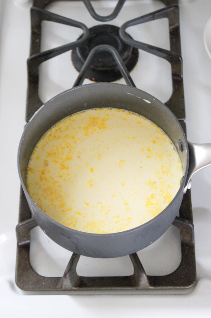 vanilla custard being cooked on a stove top in a gray pan. 