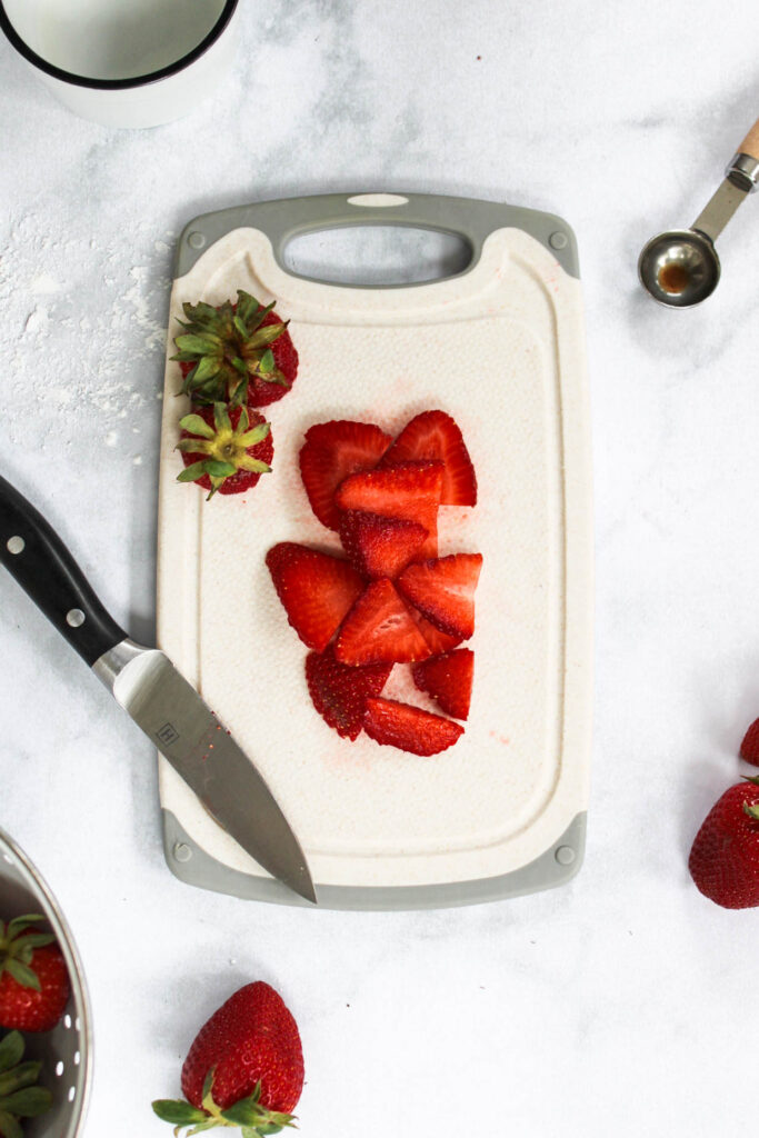 sliced strawberries on a cutting board with a knife. 