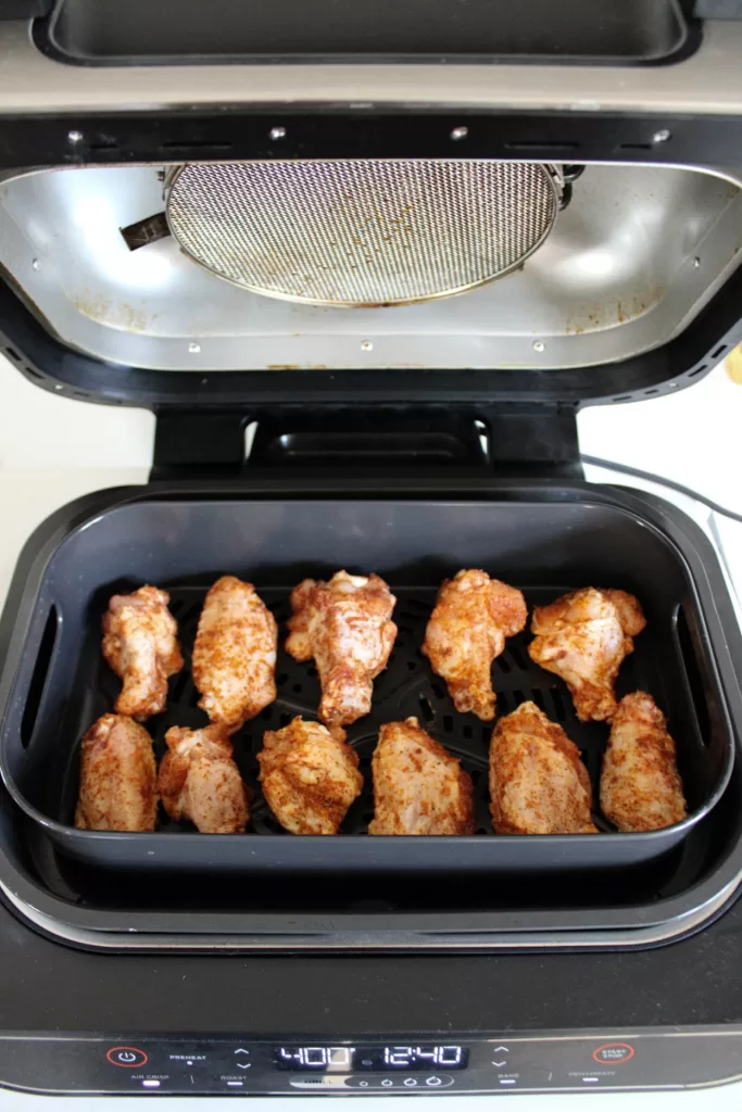 Cornstarch Chicken Wings in the air fryer with the lid open before being cooked. 