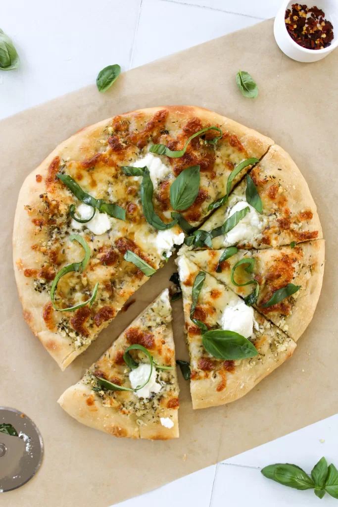 Olive oil pizza without tomato sauce topped with cheese and basil. 

