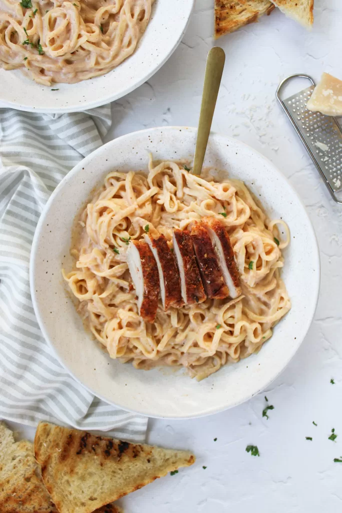 cajun chicken alfredo pasta in a stone bowl with a gold fork. 